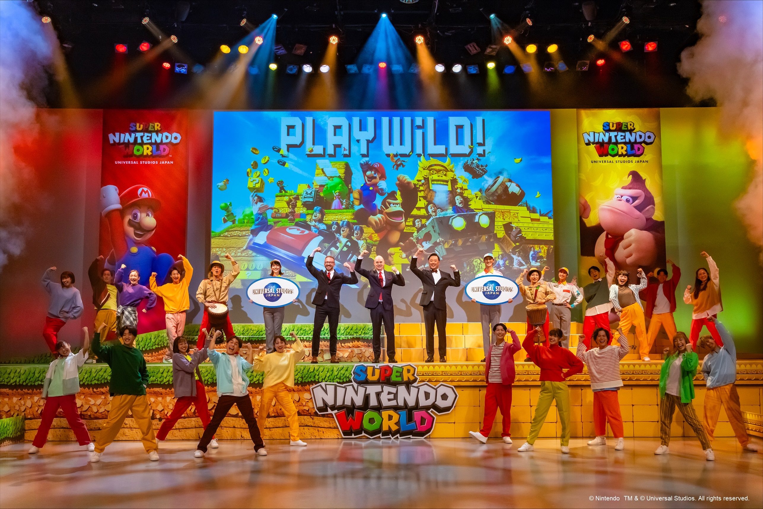 A group of people posing on stage for a Super Nintendo World press conference